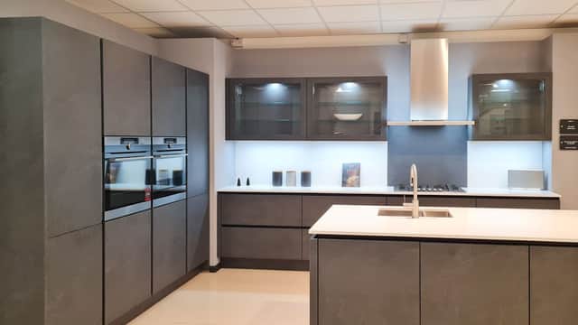 Modern kitchen display featuring sleek gray cabinetry, stainless steel appliances, and a minimalist island with a sink.