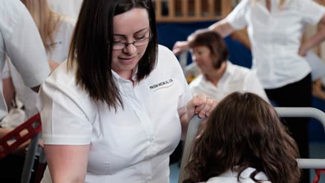 Staff in white shirts collaborate in a bright, open space, focusing on equipment at Prism Medical UK in Grange Moor.