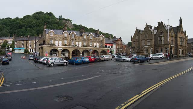 Pay & Display parking area in Settle, Yorkshire, with stone buildings, parked cars, and a hill in the background.