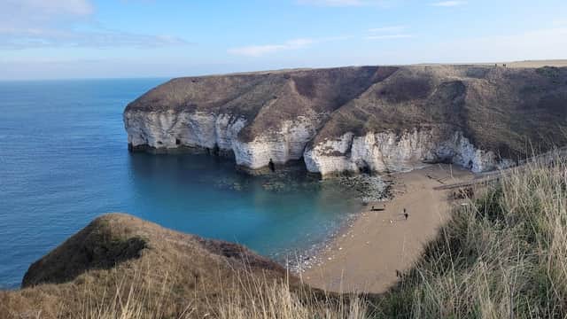 Scenic view of North Landing with cliffs, sandy beach, and calm blue sea under a clear sky in Flamborough, Yorkshire.