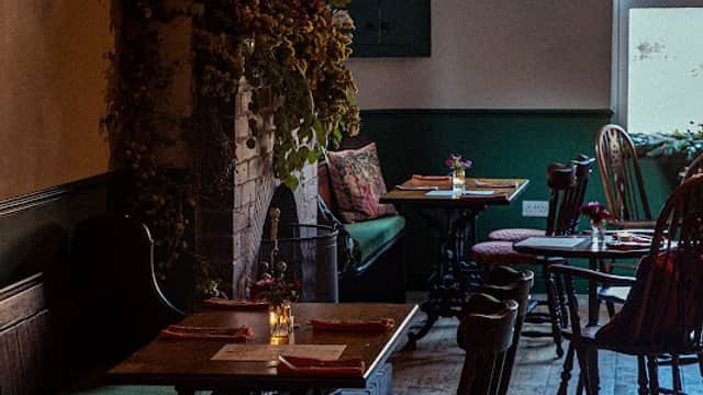 Cozy bar interior with wooden tables, chairs, and floral decorations, creating a warm, inviting atmosphere.