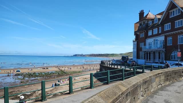 The Engine Shed at Battersby, a brick building with a sloped roof, near a sandy beach and clear blue sky.
