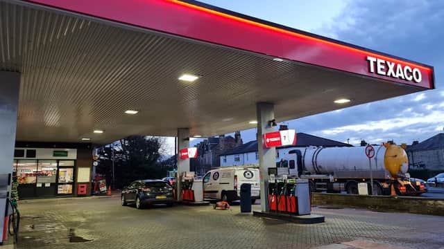Texaco garage with fuel pumps, a delivery truck, and a convenience store in Harrogate, Yorkshire, under a cloudy sky.