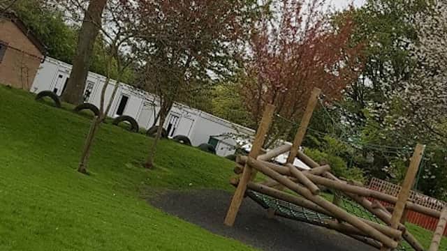 Playground equipment surrounded by trees and grassy area at Brompton-on-Swale Church of England Primary School.