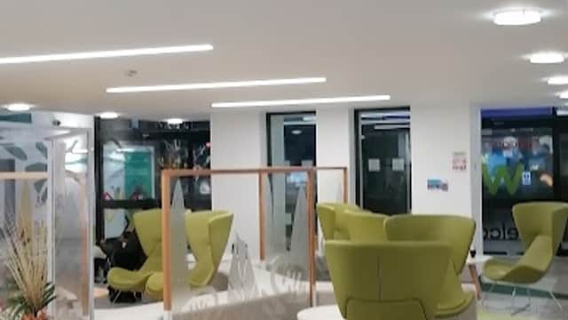Bright, modern interior with green seating, colorful flooring, and large windows in a multi-storey car park.