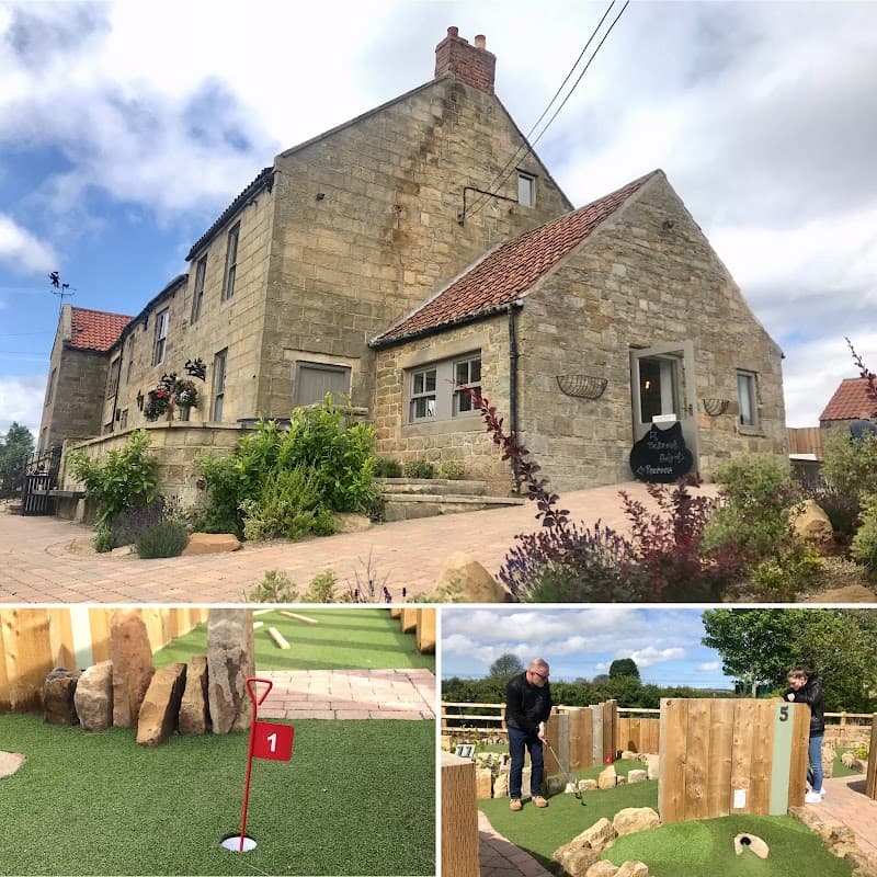 The Jack and Jill Coaching Inn features stone architecture, a sign, and a mini-golf area with a putting green and players.