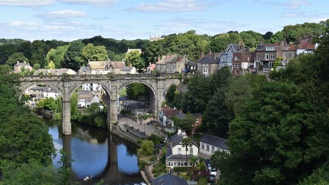 Castle Yard in Knaresborough with a view of the river, bridge, lush greenery, and charming buildings along the banks.