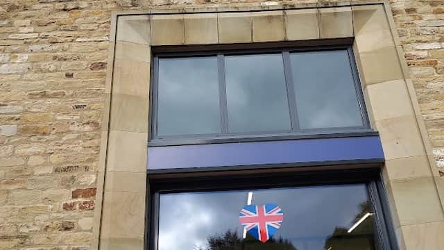 Lidl store facade with a blue and yellow logo, large windows, and a Union Jack flag hanging at the entrance.