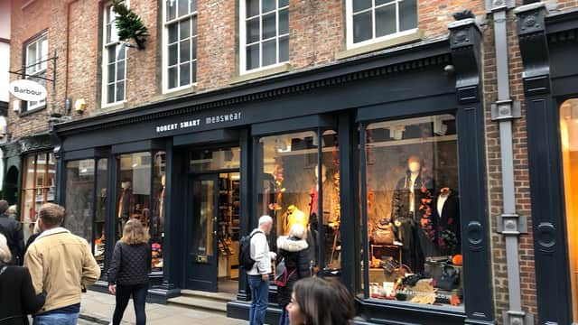Front of Robert Smart Menswear shop with stylish clothing displays and shoppers on a bustling street in York.
