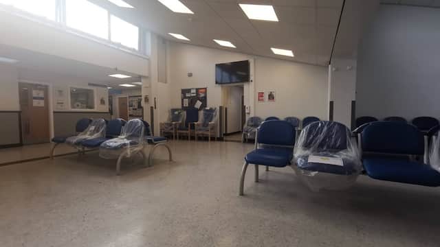 Spacious waiting area with blue chairs, a TV, and a reception desk in Hunslet Health Centre.
