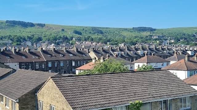 Addingham Memorial Hall with stone facade, green lawn, and blue sky, surrounded by residential buildings and hills.