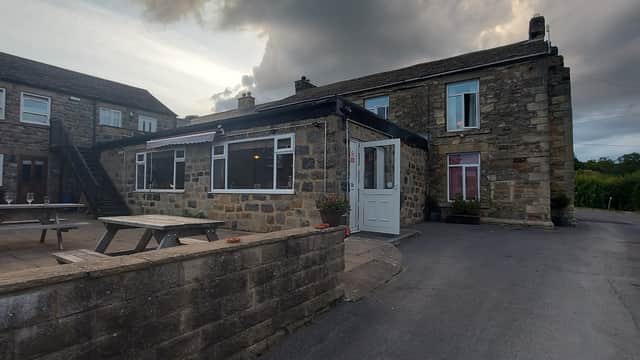 Stone building with large windows, wooden picnic tables, and a cloudy sky in Fearby, Yorkshire.