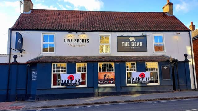 The Bear Inn features a blue facade, poppy tributes, and signs for real ales and live sports in South Cave, Yorkshire.