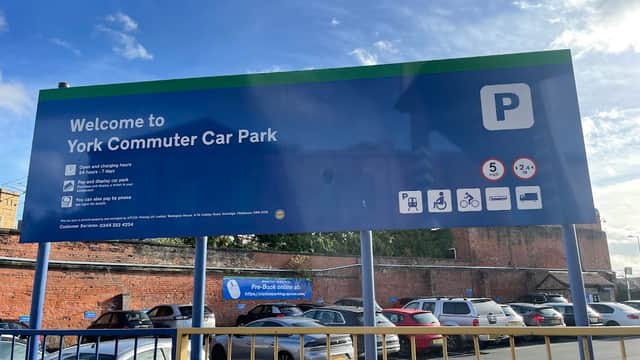 Welcome sign for York Commuter Car Park with parking details, hours, and contact information. Cars visible in foreground.