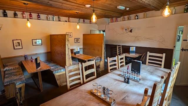 Cozy dining area with wooden tables, chairs, warm lighting, and rustic decor in The Queens Arms, Litton.