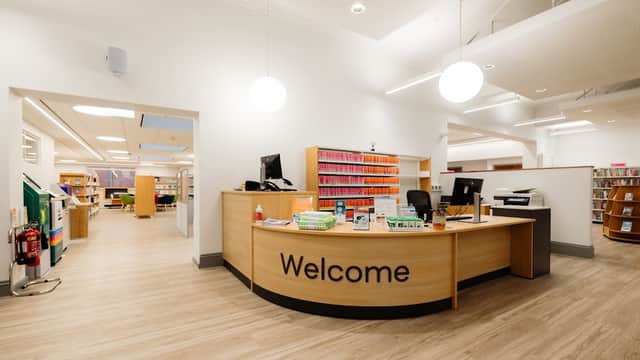 Bright, modern library interior with a welcoming reception desk and colorful book shelving in the background.