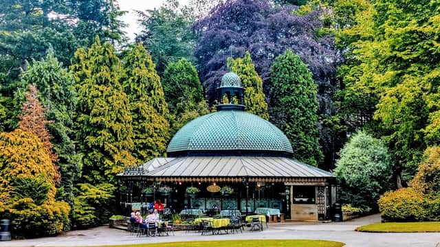 A charming octagonal pavilion surrounded by lush greenery in Valley Gardens, Harrogate, with seating and visitors.