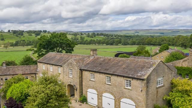 Cottages with stone facades surrounded by lush greenery and rolling hills under a cloudy sky in West Burton, Yorkshire.