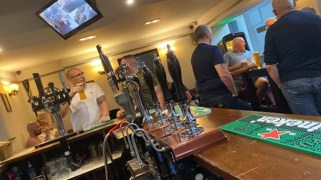 Bar scene at George & Dragon, featuring patrons, beer taps, and a TV screen in a cozy atmosphere.