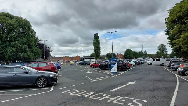 Parking lot with cars and coaches, surrounded by trees under a cloudy sky in Northallerton, Yorkshire.