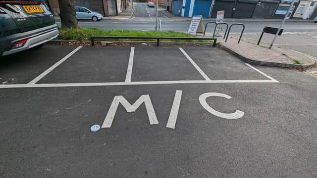 Free parking area with marked spaces, featuring the letters "MIC" on the pavement, near shops in Attercliffe.