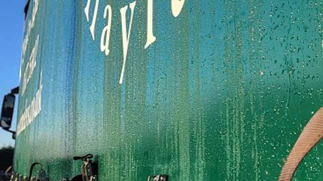 Green truck side with "Skerne Leys Haylage" logo and dew droplets, set against a clear blue sky.