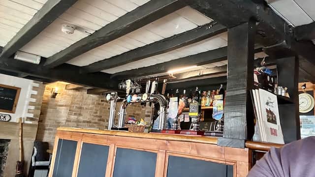 Interior view of the Witching Post Inn featuring a wooden bar, beer taps, and a cozy, rustic atmosphere.