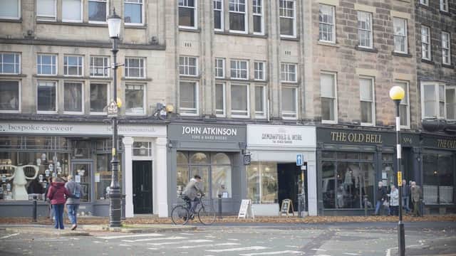 John Atkinson Fine & Rare Books storefront, with pedestrians and a cyclist on a tree-lined street in Harrogate, Yorkshire.