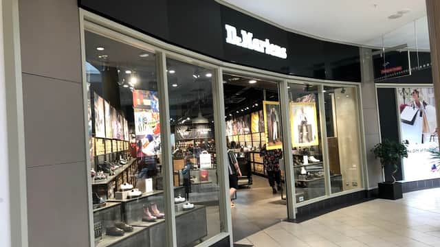 Entrance of Dr. Martens shoe shop featuring large windows, displays of footwear, and vibrant wall art.