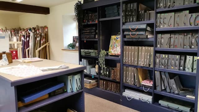 Interior of Wath Court Fabrics shop featuring shelves of fabric samples, swatches, and a display table.