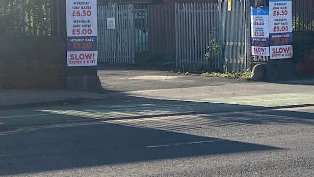 Entrance to Marsh Lane Car Park with signage displaying parking rates and instructions, flanked by brick pillars.