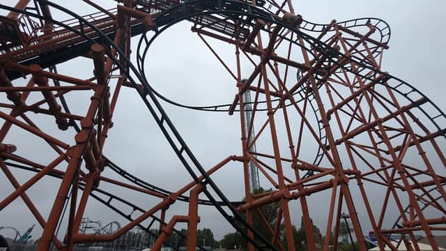 Orange roller coaster structure with loops and twists against a cloudy sky in Kirby Misperton, Yorkshire.