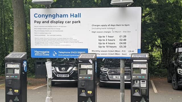 Sign for Conyngham Hall pay and display car park with pricing details; parked cars visible in the background.