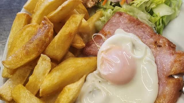 Plate of golden fries, a fried egg, ham, and a fresh salad with coleslaw and mixed vegetables.
