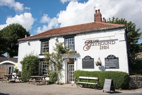 Charming Bed & Breakfast with white exterior, red roof, outdoor seating, and lush greenery in Hackforth, Yorkshire.