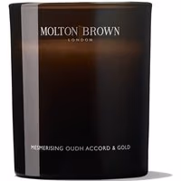 Dark brown Molton Brown candle with white text, labeled "Oudh Accord & Gold," in a sleek glass container.