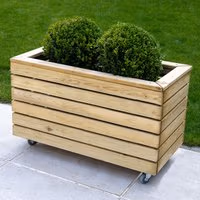 Wooden garden planter with horizontal slats, two green shrubs, and wheels for mobility, measuring 2'7 x 1'4.